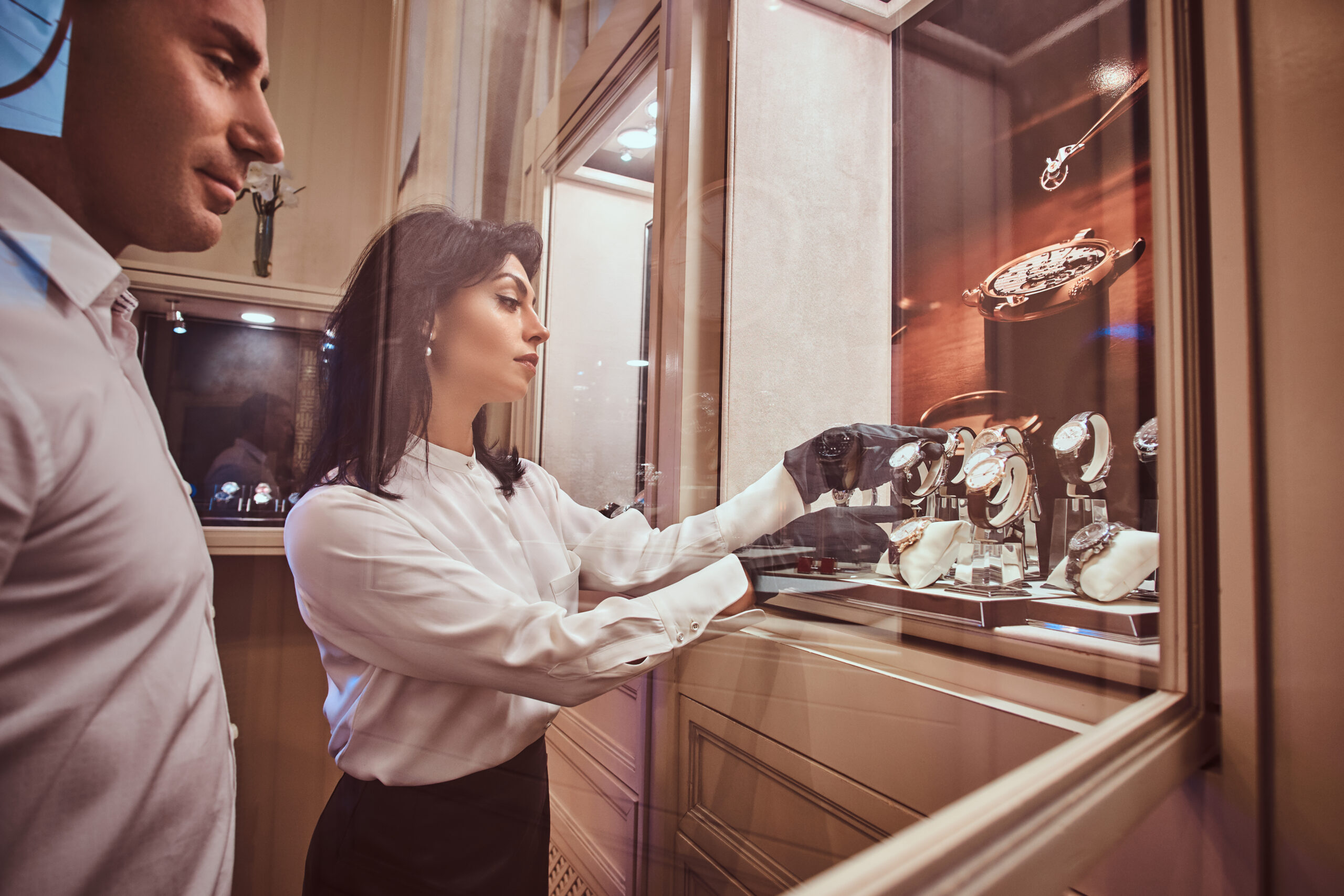 What Is Clienteling in Luxury Retail and Why Does It Matter?: №1 | Simply Contact Seller shows the client an exclusive men's watch standing next to open showcase in the luxury jewelry store